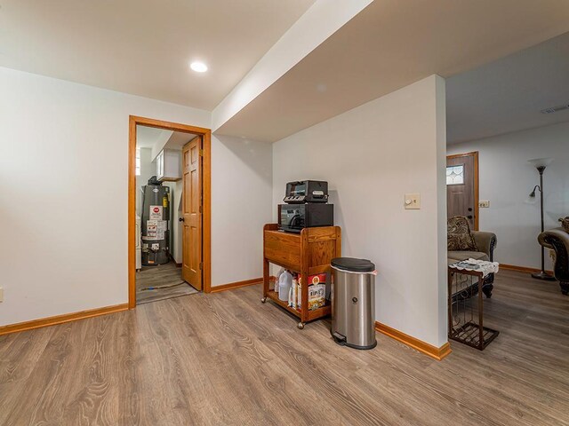 hallway with gas water heater and light hardwood / wood-style flooring