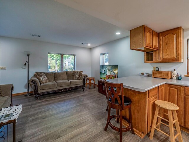 kitchen with kitchen peninsula, dark hardwood / wood-style floors, and a breakfast bar area