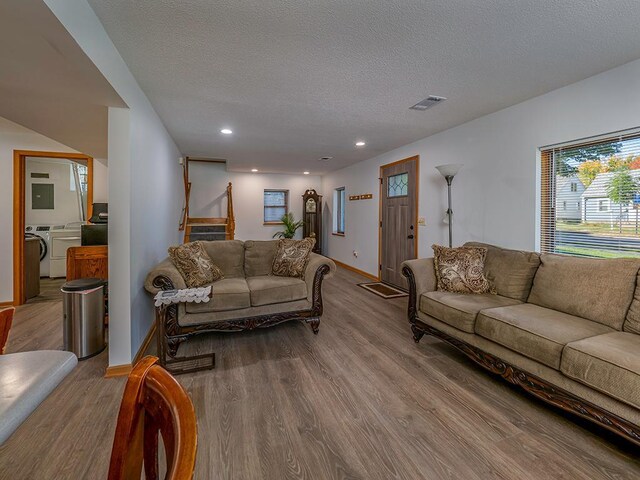 living room featuring a textured ceiling, washer / dryer, and light hardwood / wood-style flooring