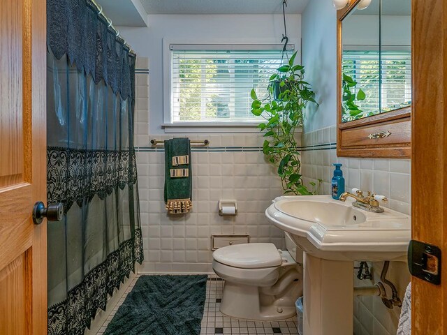 bathroom with tile walls, tile patterned flooring, toilet, and a shower with shower curtain