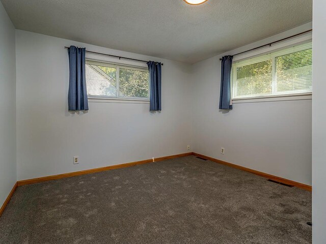 carpeted empty room featuring a textured ceiling