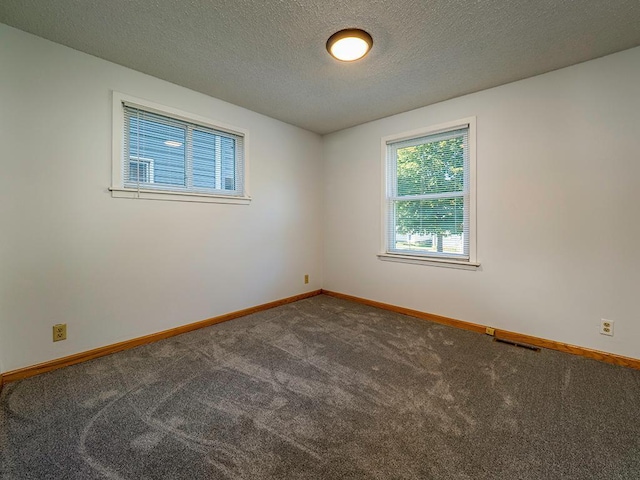carpeted empty room with visible vents, baseboards, and a textured ceiling