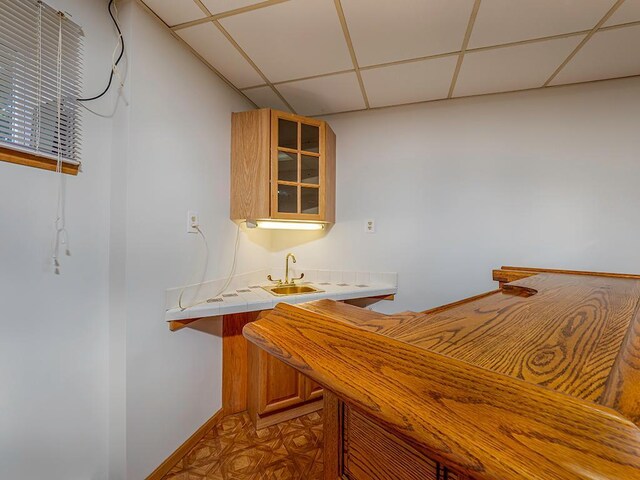 bar featuring a paneled ceiling and tile counters