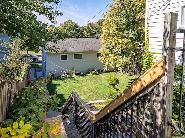 rear view of house featuring a lawn, a wooden deck, a shingled roof, and a fenced backyard