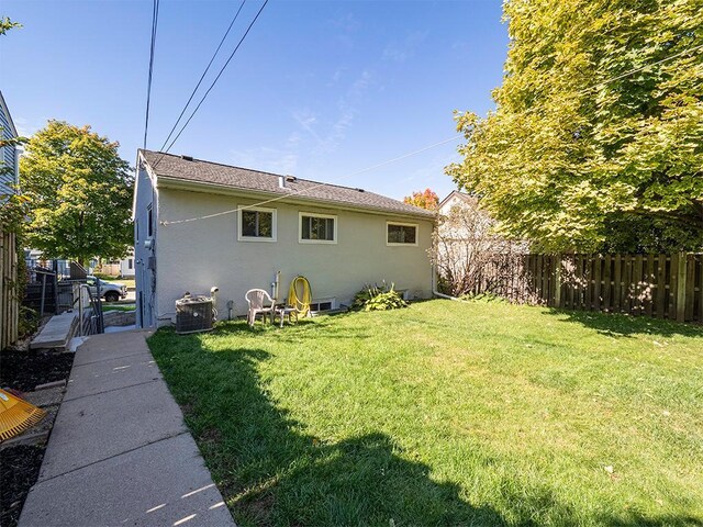 back of property featuring central AC unit and a yard