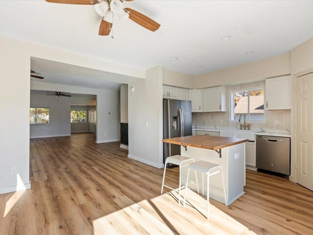 kitchen featuring white cabinets, stainless steel appliances, sink, a kitchen breakfast bar, and butcher block countertops