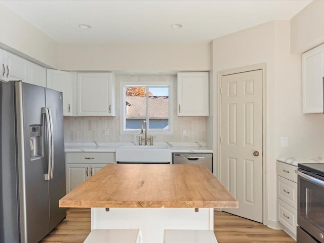 kitchen featuring white cabinets, stainless steel appliances, a center island, and tasteful backsplash