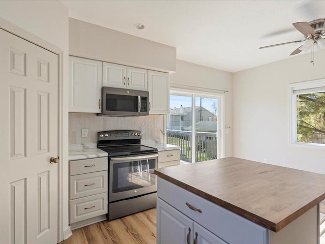 kitchen featuring light wood-type flooring, white cabinetry, butcher block counters, and appliances with stainless steel finishes