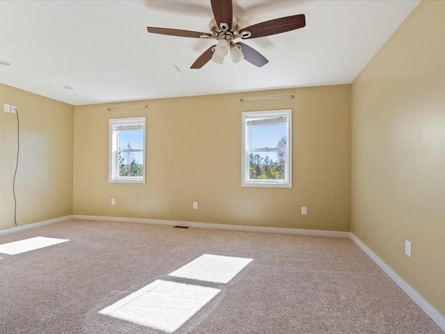 spare room featuring ceiling fan, light colored carpet, and a wealth of natural light