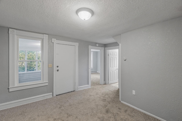 spare room featuring a textured ceiling and light colored carpet