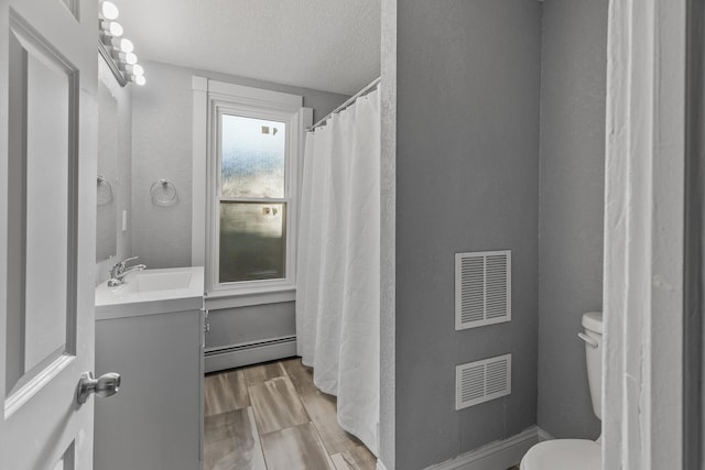 bathroom featuring a baseboard heating unit, toilet, hardwood / wood-style flooring, vanity, and a textured ceiling