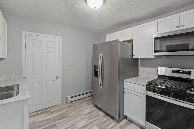 kitchen with light hardwood / wood-style flooring, stainless steel appliances, light stone countertops, a baseboard heating unit, and white cabinetry