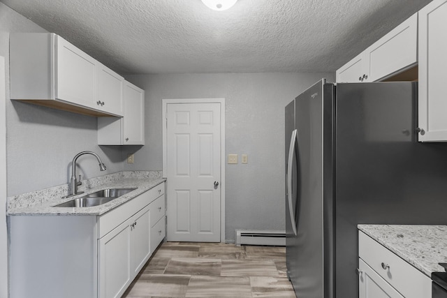 kitchen with stainless steel refrigerator, light hardwood / wood-style floors, sink, and white cabinetry