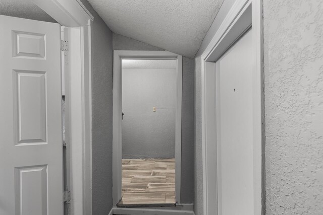 hallway featuring lofted ceiling and a textured ceiling