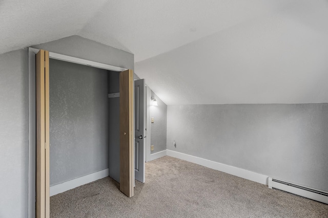 additional living space with a textured ceiling, baseboard heating, carpet flooring, and vaulted ceiling