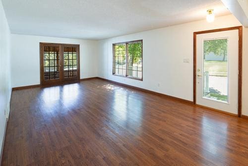 spare room with dark wood-type flooring and french doors