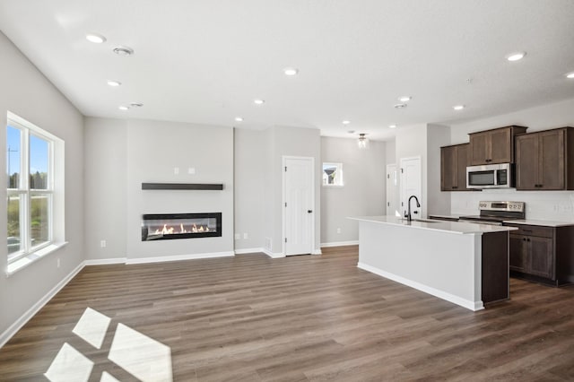 kitchen with an island with sink, stainless steel appliances, and dark wood-type flooring