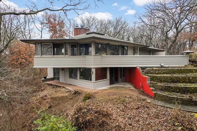 back of property featuring a sunroom and a chimney