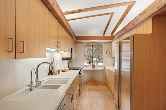 kitchen featuring light wood finished floors, stainless steel appliances, light countertops, under cabinet range hood, and beam ceiling