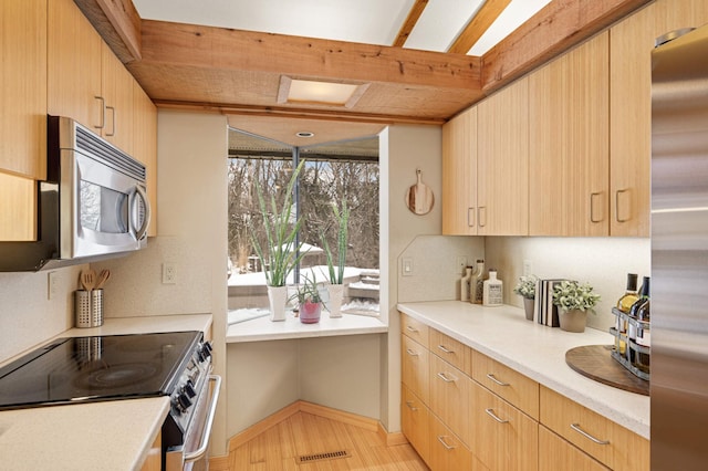 kitchen with light brown cabinetry, light countertops, appliances with stainless steel finishes, and visible vents