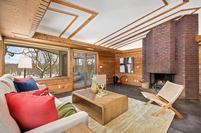 living room with wooden walls, vaulted ceiling, a fireplace, and wood finished floors