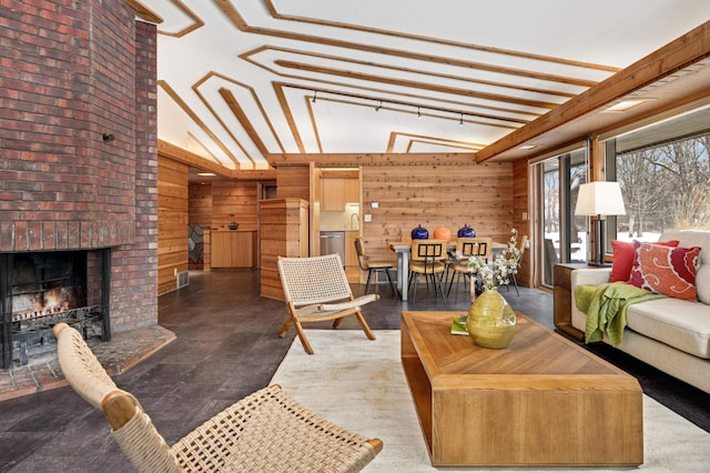 living room featuring wooden walls, high vaulted ceiling, a fireplace, and beamed ceiling