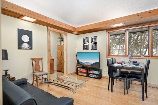 living room with light wood-type flooring, baseboards, visible vents, and lofted ceiling