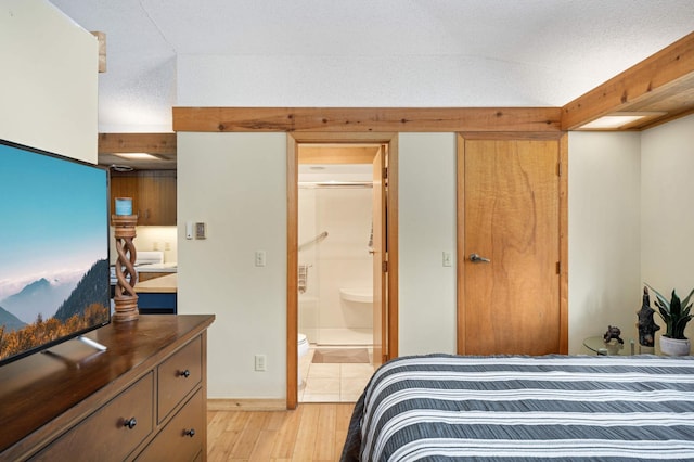 bedroom with light wood-type flooring and ensuite bathroom