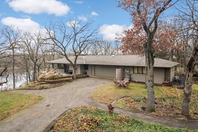 single story home featuring driveway, a front lawn, and a water view