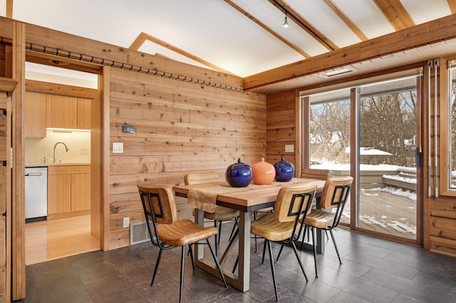 dining space with lofted ceiling with beams and wood walls