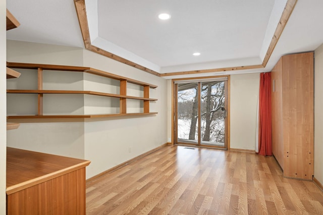 spare room with light wood finished floors, recessed lighting, a raised ceiling, visible vents, and baseboards