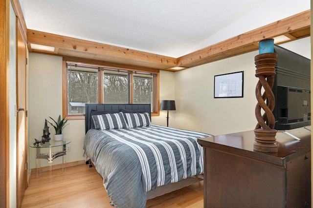 bedroom with baseboards, a textured ceiling, and light wood-style floors