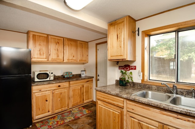 kitchen featuring black fridge, sink, crown molding, and a textured ceiling