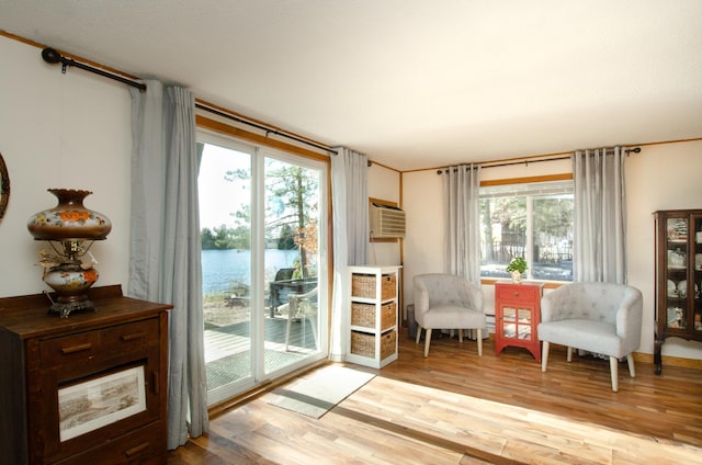 living area with a wall mounted air conditioner, light hardwood / wood-style floors, and a water view