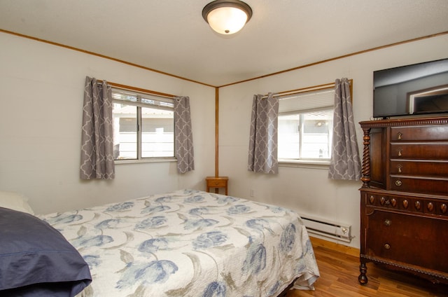 bedroom featuring multiple windows, crown molding, a baseboard radiator, and wood-type flooring