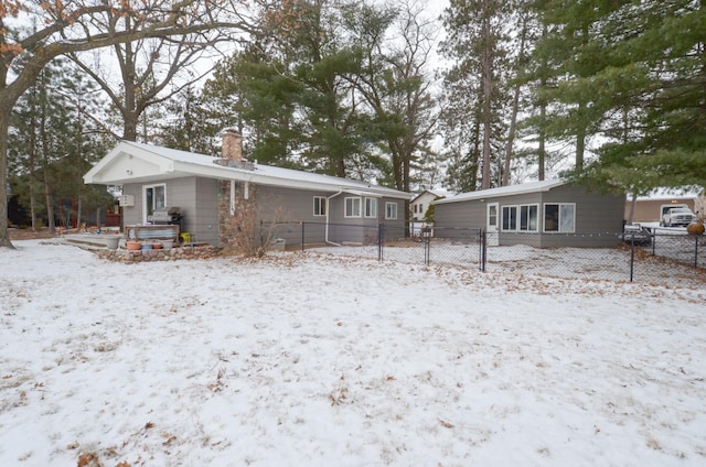 snow covered property featuring fence and a chimney