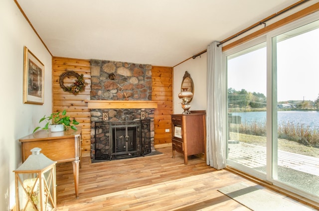 living area with a water view, a fireplace, ornamental molding, and wood finished floors