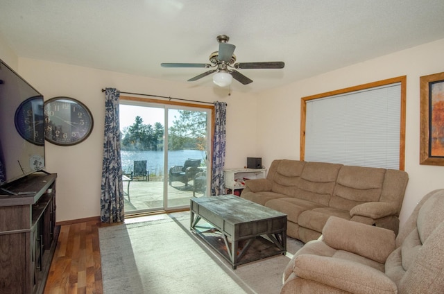 living room featuring a water view, ceiling fan, baseboards, and wood finished floors