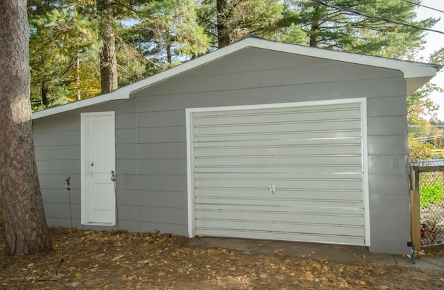 detached garage featuring a storage unit and fence