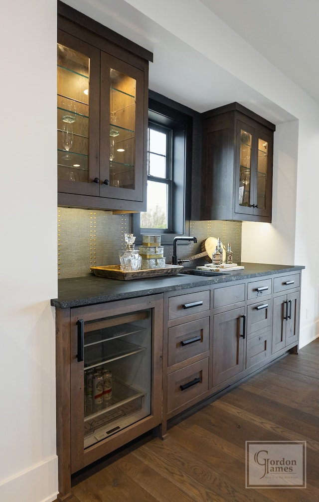 bar featuring stainless steel fridge, dark brown cabinets, dark hardwood / wood-style flooring, and tasteful backsplash