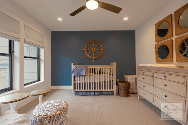 carpeted bedroom featuring a crib, washer / dryer, and ceiling fan