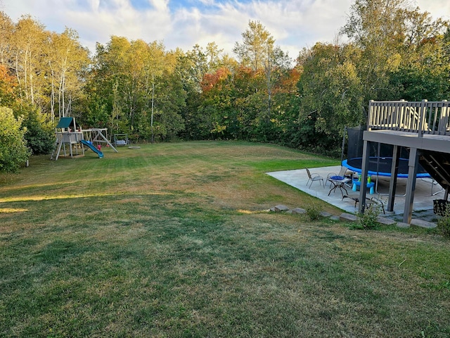 view of yard featuring a playground, a wooden deck, and a patio