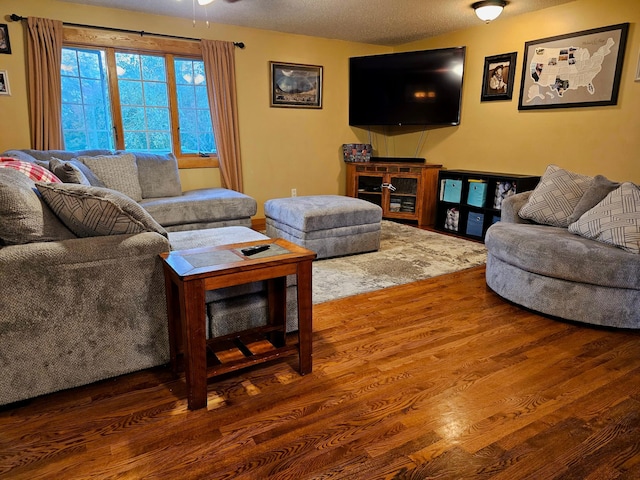 living room with ceiling fan, hardwood / wood-style flooring, and a textured ceiling