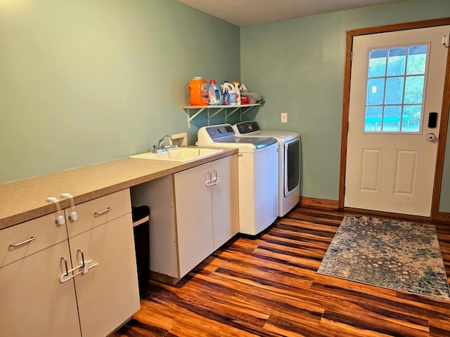 laundry area featuring washing machine and clothes dryer, cabinets, sink, and dark hardwood / wood-style flooring