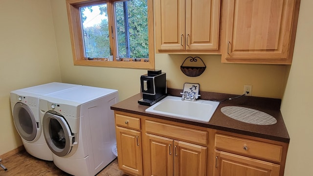 clothes washing area with sink, washer and clothes dryer, and cabinets