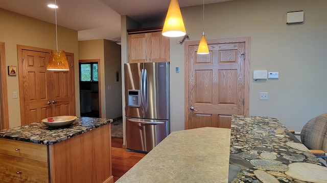 kitchen featuring stainless steel fridge with ice dispenser, decorative light fixtures, and a kitchen island