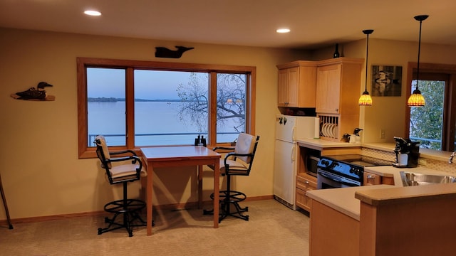 kitchen with light brown cabinets, a healthy amount of sunlight, sink, a water view, and electric range oven