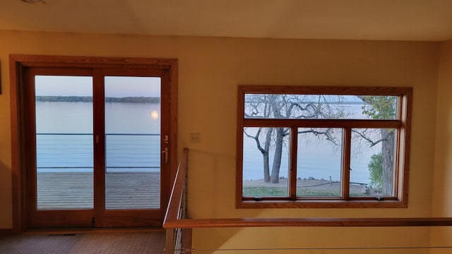 entryway featuring plenty of natural light, french doors, a water view, and carpet