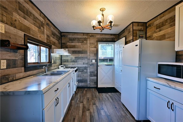 kitchen featuring pendant lighting, white appliances, wood walls, and white cabinetry