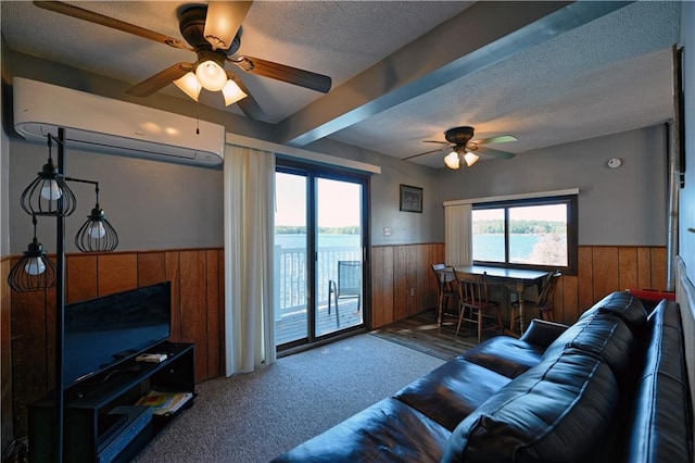 carpeted living area featuring wooden walls, wainscoting, a wall mounted air conditioner, a textured ceiling, and a ceiling fan
